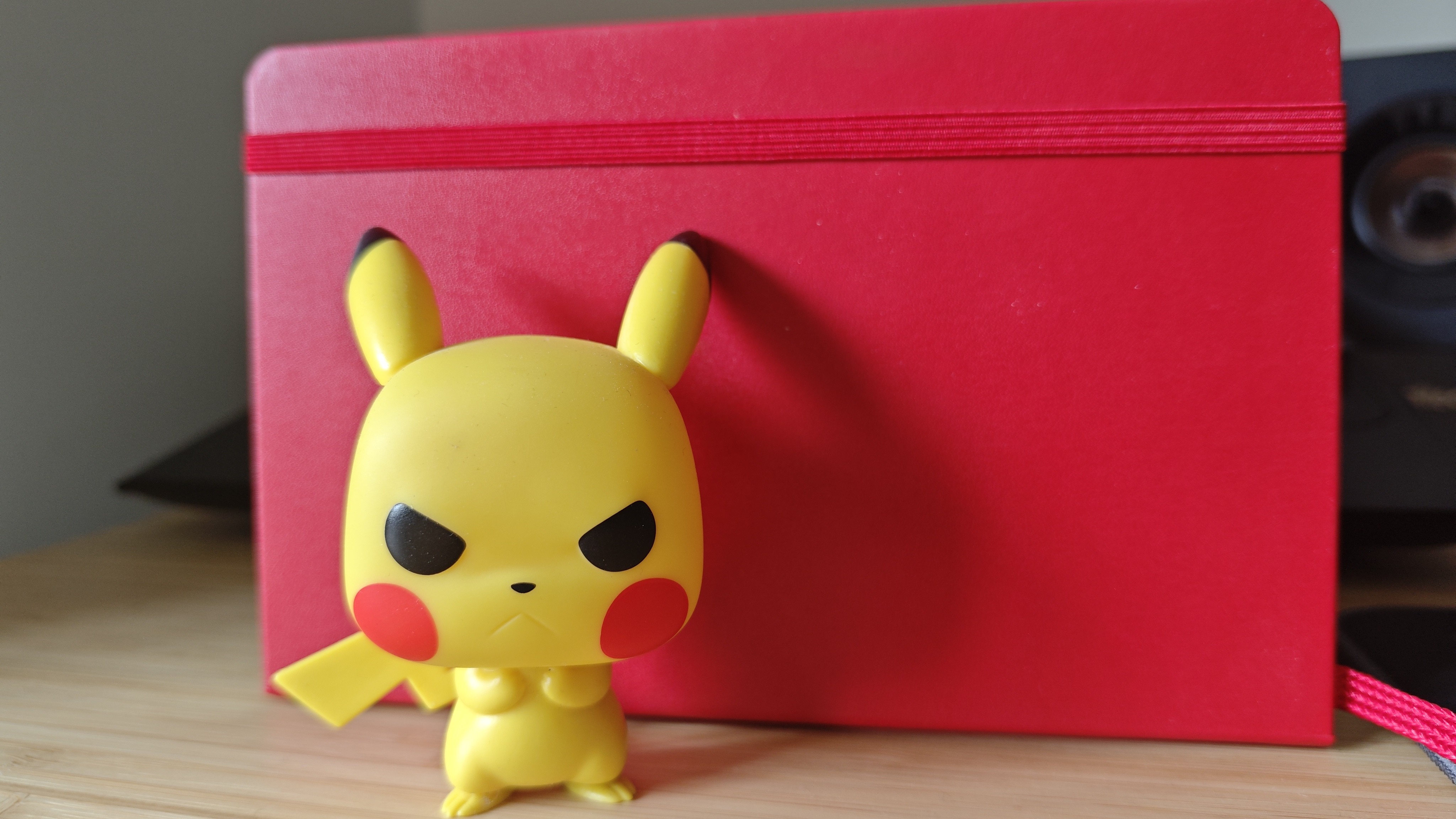 Image of a Pikachu Pop Vinyl figure against a red notebook shot on a Poco F7 Pro phone