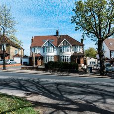 Street of semi-detached houses with tarmac driveways off a main road