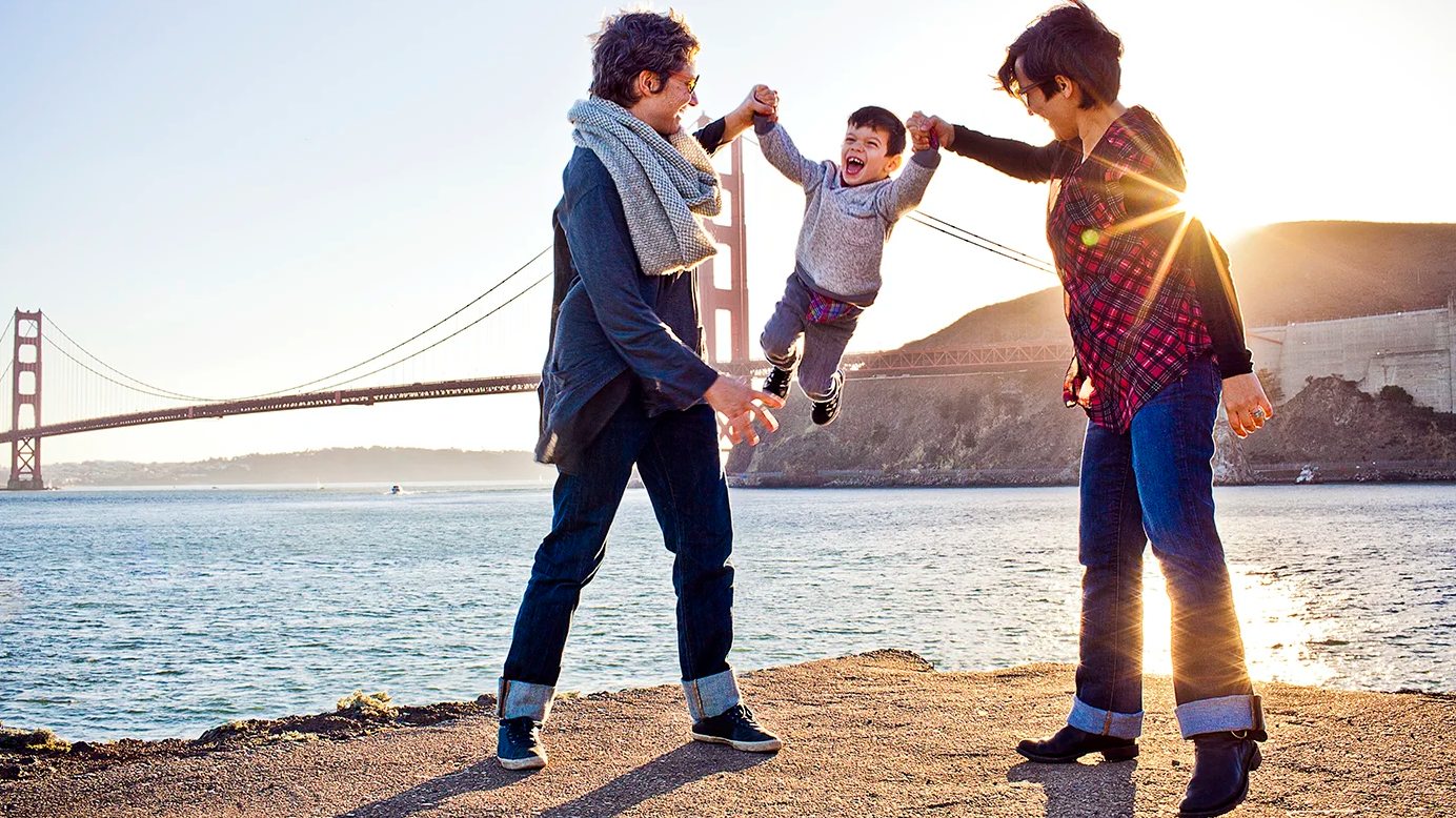 A family holding their child in front of the Golden Gate Bridge.