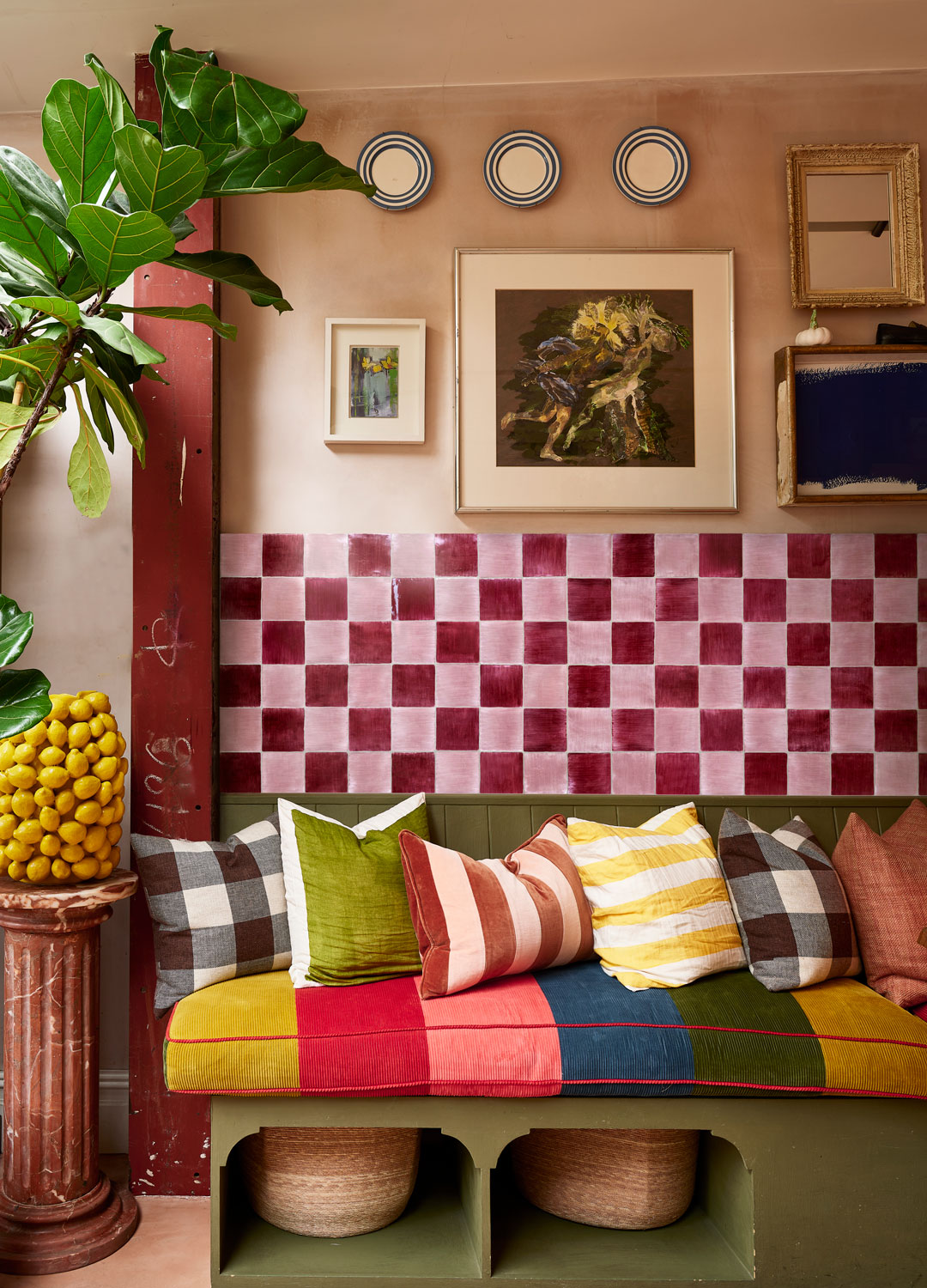 colourful seating area with pink wall tiles and green wooden bench with brightly coloured cushions