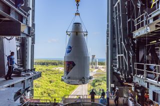 The Lucy spacecraft enclosed in its fairing being lifted onto its rocket in preparation for launch.