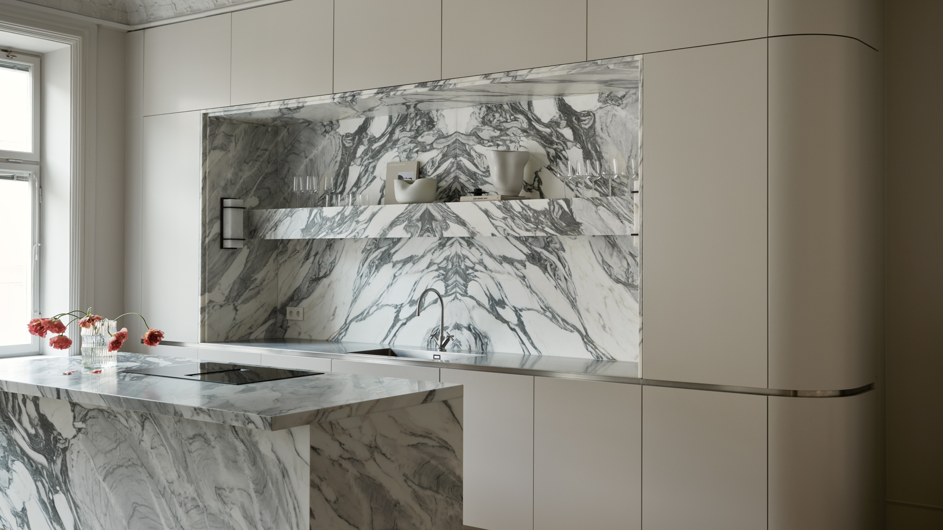 modern grey kitchen with curved cabinetry and a dramatic marble island and splashback