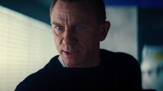 Daniel Craig stands in the lab, looking concerned, in No Time To Die.