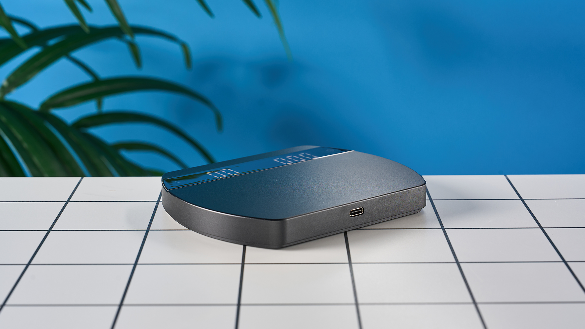 a luxury coffee scale made by Felicita Arc is photographed against a blue background with its weight, USB-C cable and silicone mat