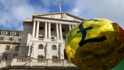 A gold balloon with a pound sign is raised in front of the Bank of England