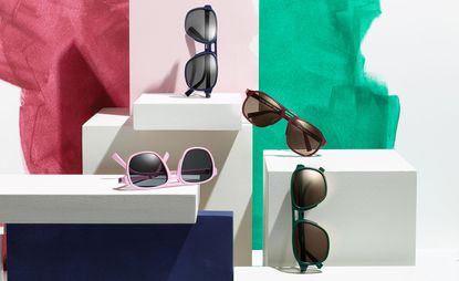 Four pairs of sunglasses in different coloured frames, positioned on white boxes with a colourful background