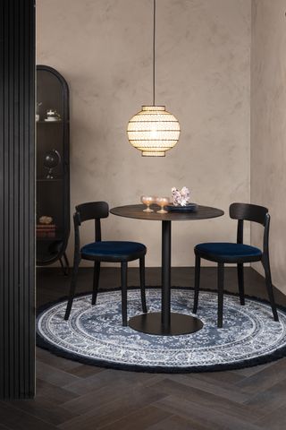 small round dining table with two chairs in a dark dramatic dining room