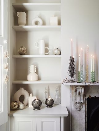 white bookshelf decorated with christmas candles