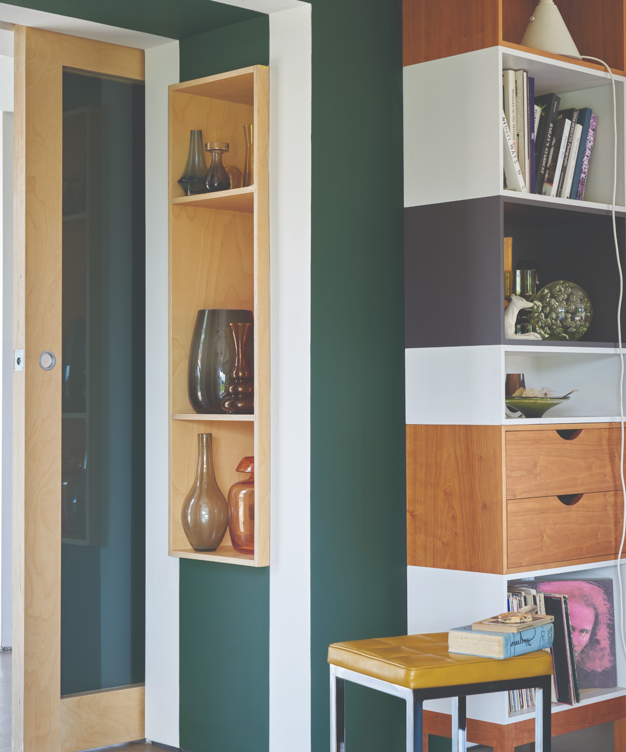 A small hallway painted in Farrow &amp;amp; Ball&#039;s Studio Green shade with a display cabinet of vases