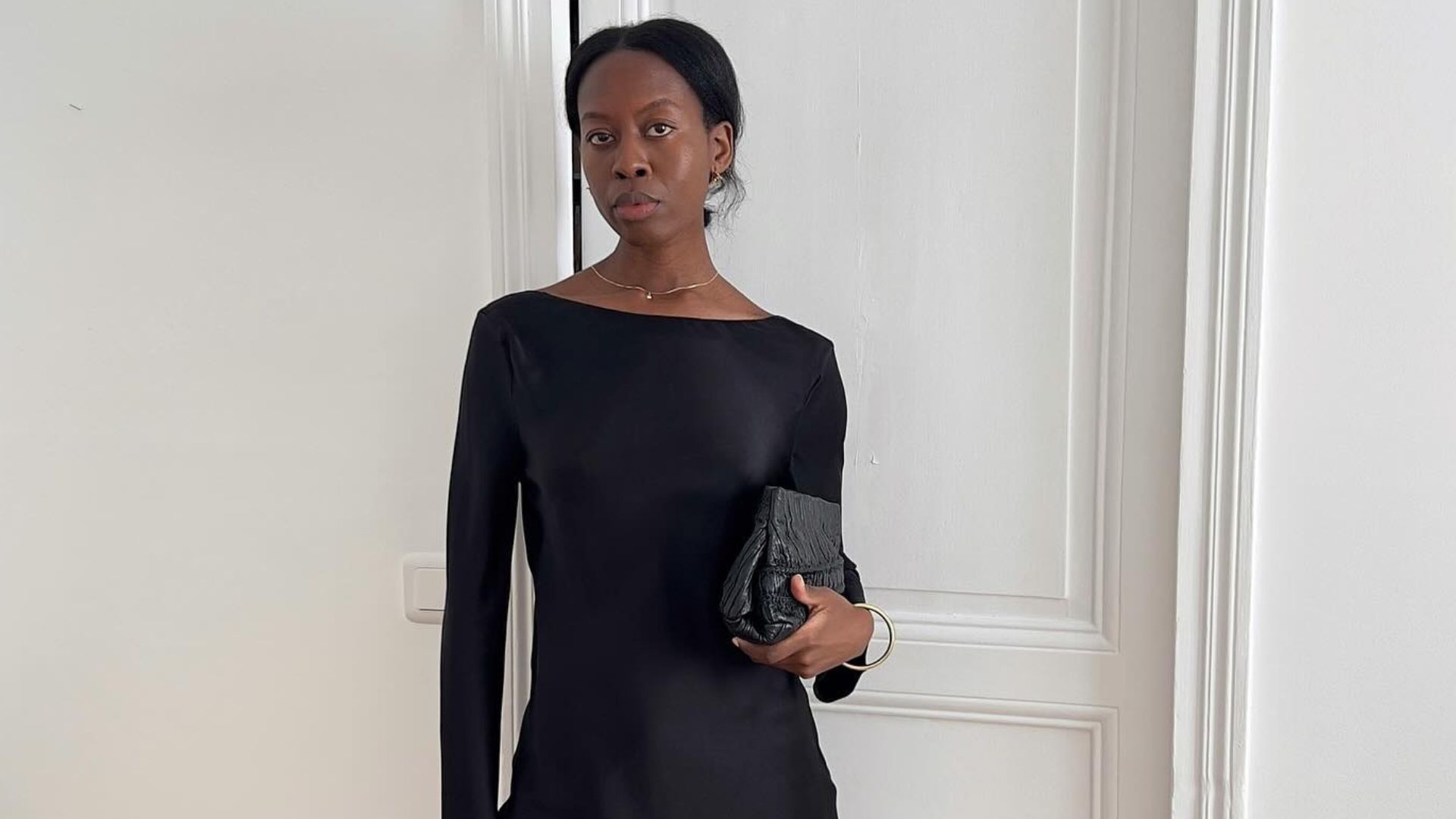Influencer @sylviemus_ wears a black satin blouse with black capri pants and heeled mules.