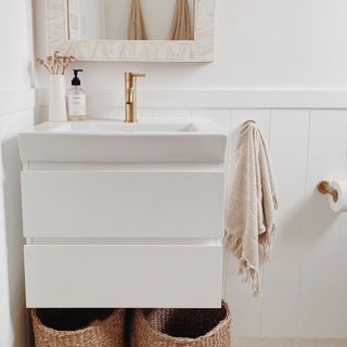 white bathroom with closeup of sink and woven baskets under sink