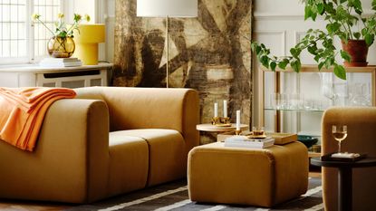 IKEA Stockholm collection with beige modular sofa and ottoman, glass cabinet with pot plant, candlesticks, books, artwork, floor lamp