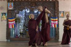 A novice Buddhist monk helps a younger novice to wear his robe at Bahan Thone Htat monastic school in Yangon, Myanmar.