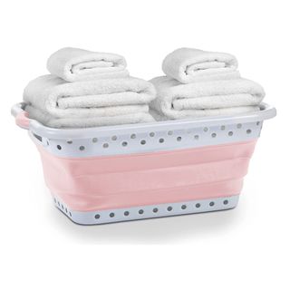 A pink collapsible laundry basket with towels in it 