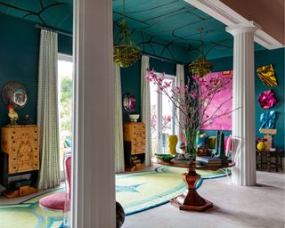 grand entrance room with teal walls, maximalist decor and teal wallpapered ceiling