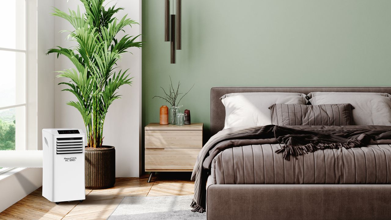 Bedroom with green wall, grey bed and white air conditioning unit.