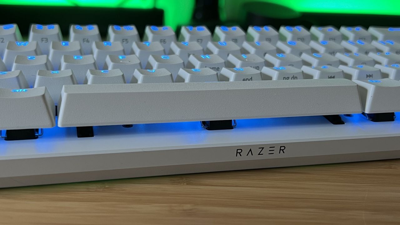Close up on Razer logo of the Razer Huntsman V3 Pro Mini gaming keyboard with RGB underglow on white chassis