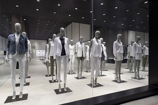 A series of mannequins wearing goods from the showroom, predominantly white, grey and blue in colour.