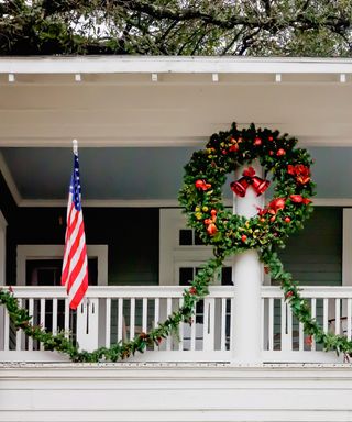 A historic home decorated for Christmas with traditional wreath and flag