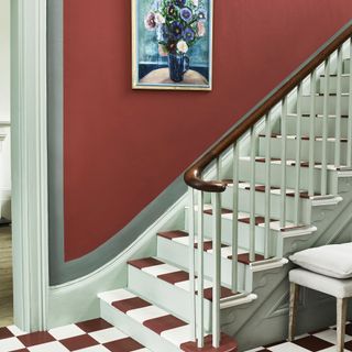 dark red wall in hallway leading up stairs with checked floor tiles in white and red