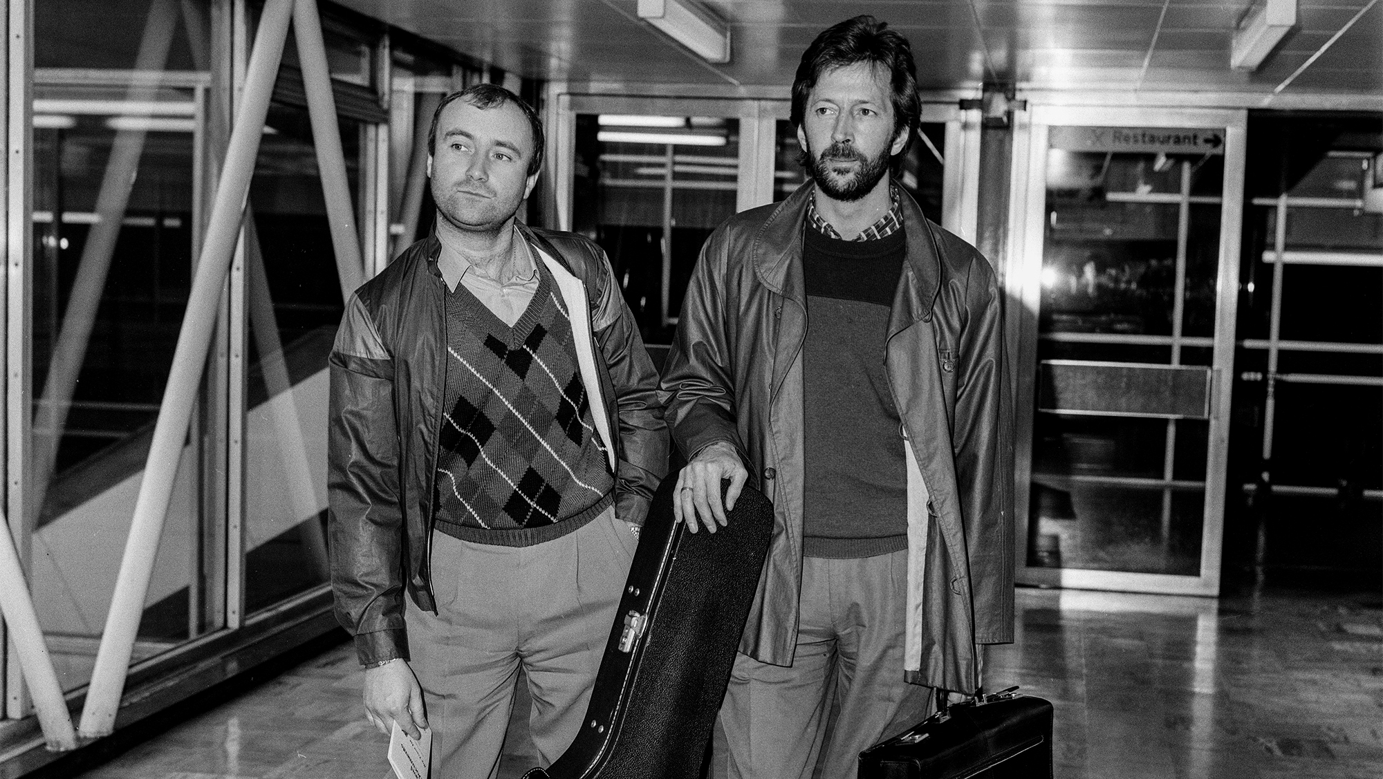 Phil Collins and Eric Clapton leaving Heathrow Airport for Barbados, where they are to make a new record. They will be away for a month. 6th March 1984.