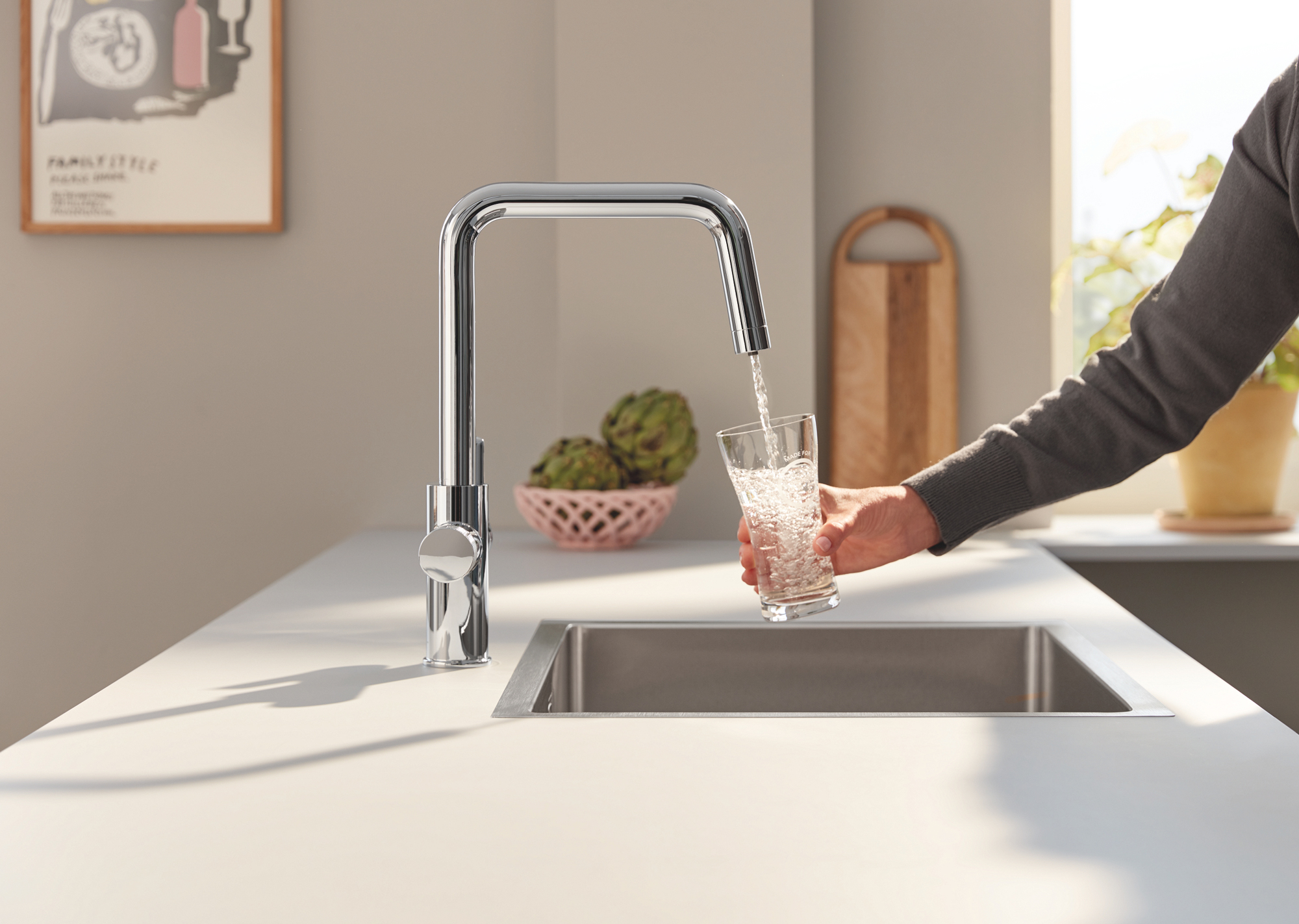 a person filling a glass from an angular kitchen tap