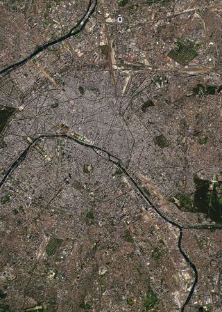 A satellite image of a busy city with rivers cutting it in two places.