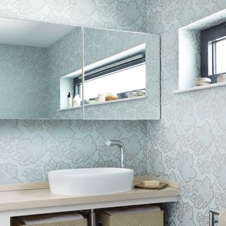 blue printed wallpaper on wall mirror on wall and wash basin