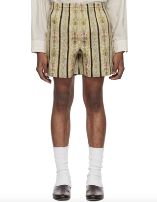 a model stands in front of a white backdrop wearing a pair of floral brocade shorts and ballet flats