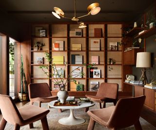 A mid-century modern library with brown chairs and floor-to-ceiling bookshelves