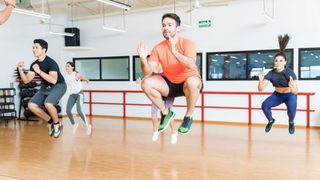 Group of people in exercise class performing tuck jumps