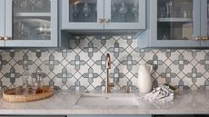 pale blue kitchen cabinets with brass kitchen tap and marble worktop