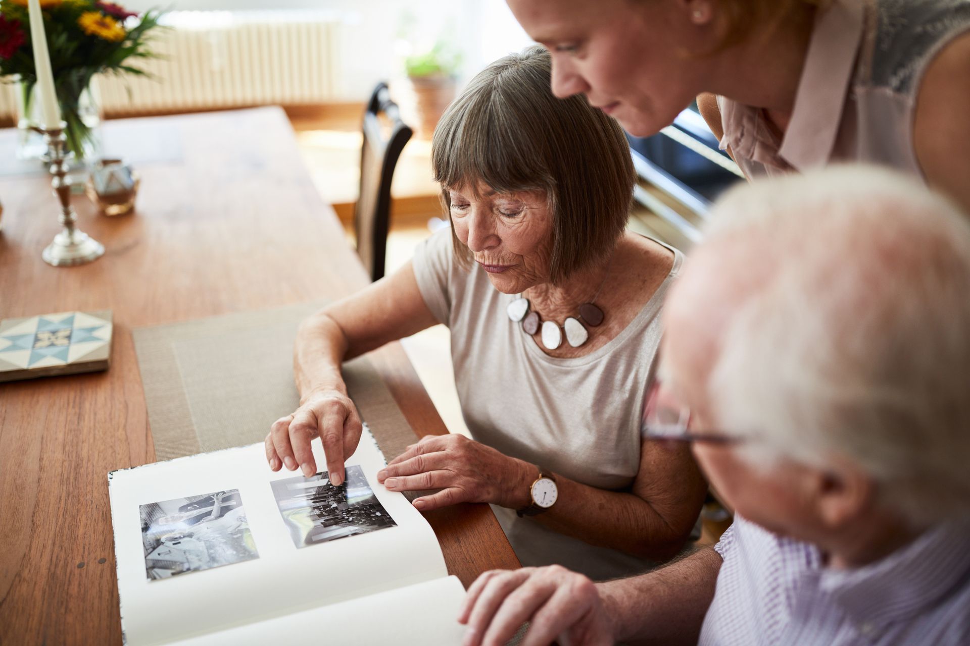 An older couple looks at a photo album with a younger person.