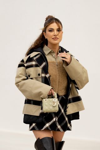 Paris fashion week guest wearing a flannel barn jacket, sherpa shirt, and plaid skirt.