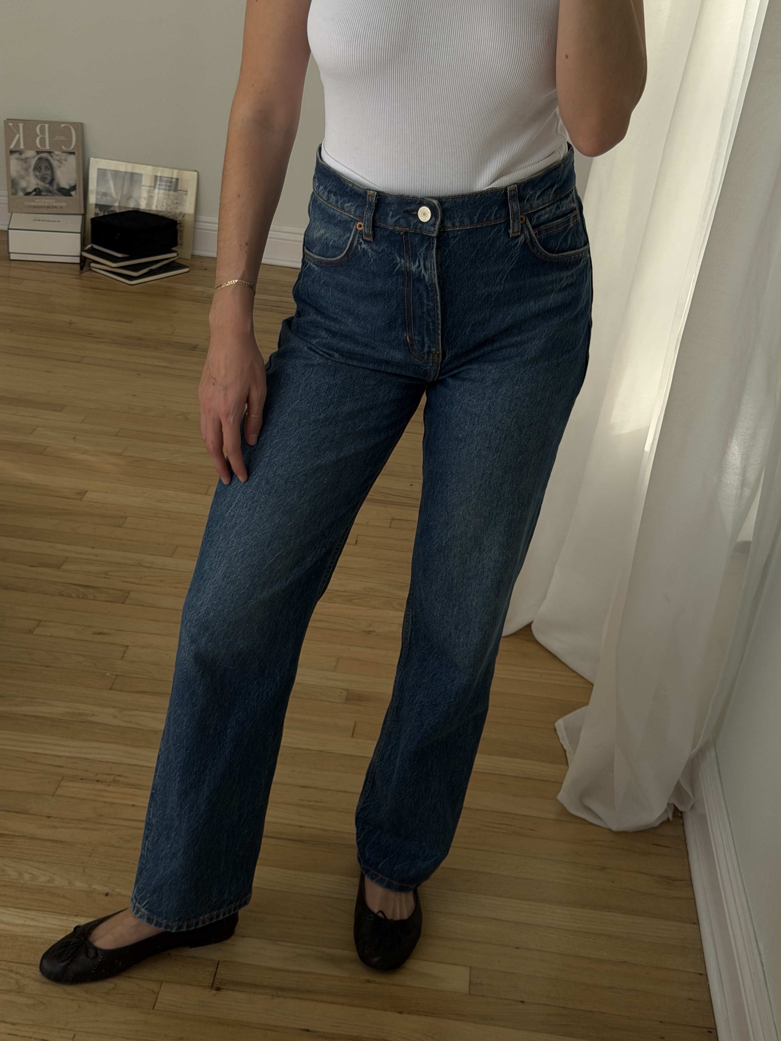 Kathryn Zahorak posing in mirror wearing white t-shirt, jeans, and black ballet flats 