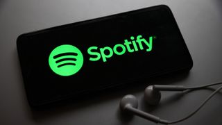 Spotify logo on a smartphone with headphones next to it