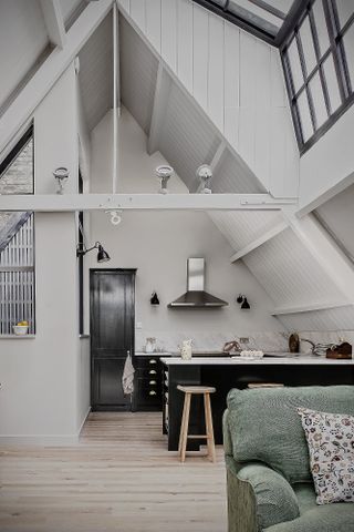 Open plan kitchen in a loft conversion with high ceilings, white walls, dark blue cabinets