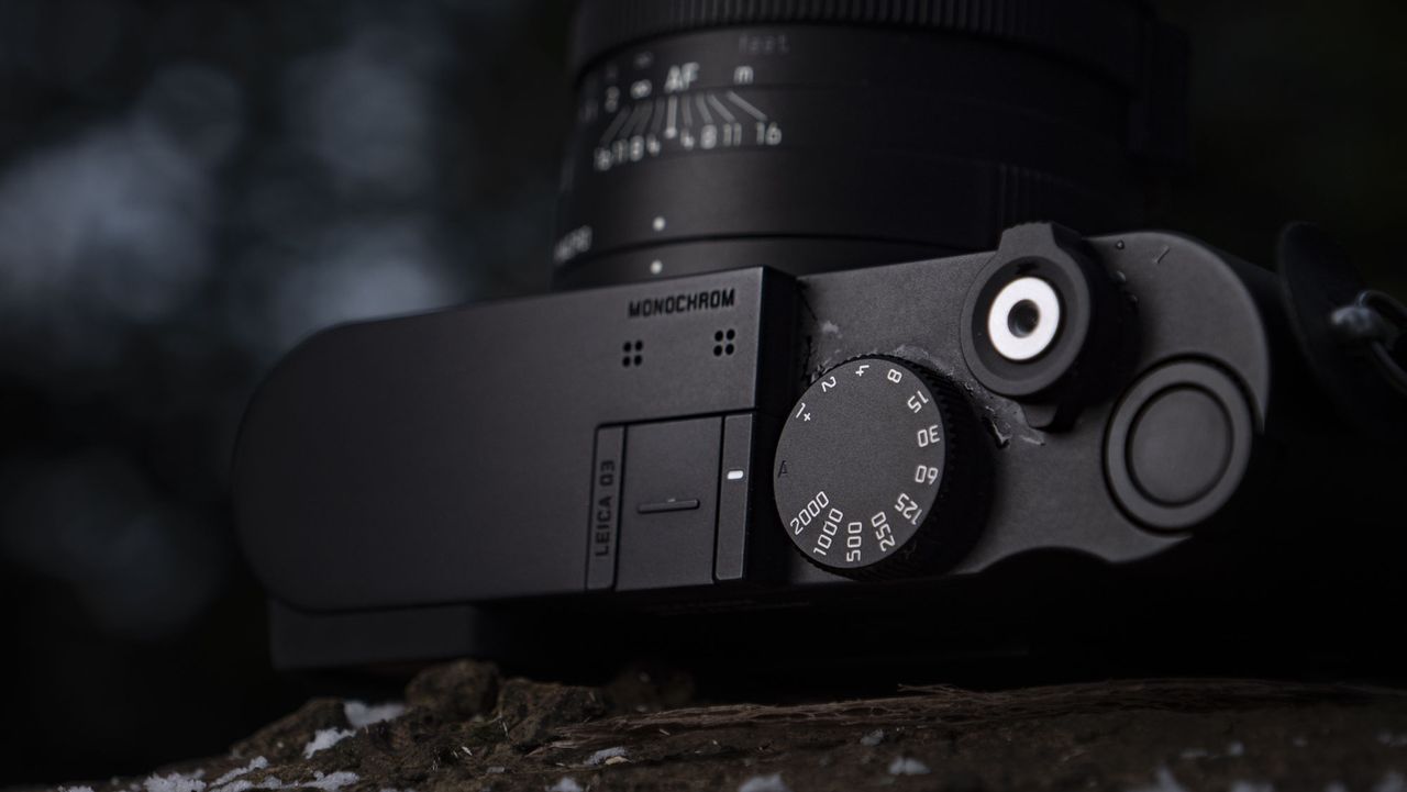 Leica Q3 Monochrom compact camera outside on a snow-dusted log