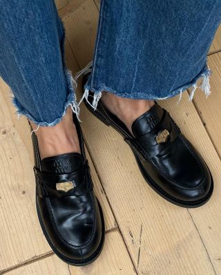 Woman wearing jeans and Miu Miu penny loafers.