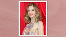 Image of Trinny Woodall smiling with curly highlighted brunette long bob and wearing an iridescent halterneck gown, on a mauve background