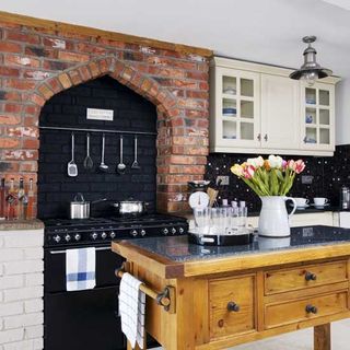 kitchen with brick wall wooden storage table and black gas stove
