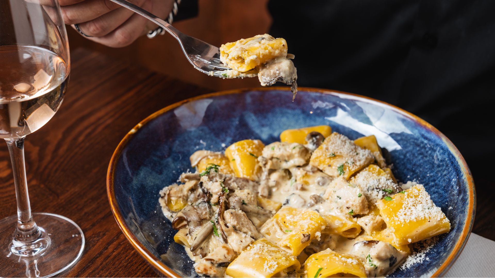 an image of the chicken and mushroom pasta dish at 27 Old Compton St. It is on a blue ceramic pasta bowl on top of a wooden table