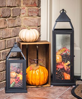 Halloween door decor ideas with black lanters filled with autumn leaves, and miniature pumpkins