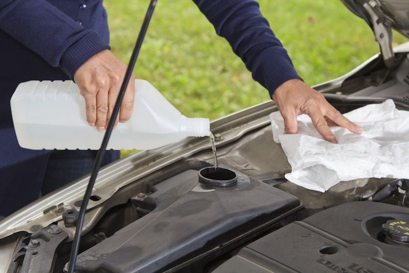 A man pours windshield washer fluid into his car.