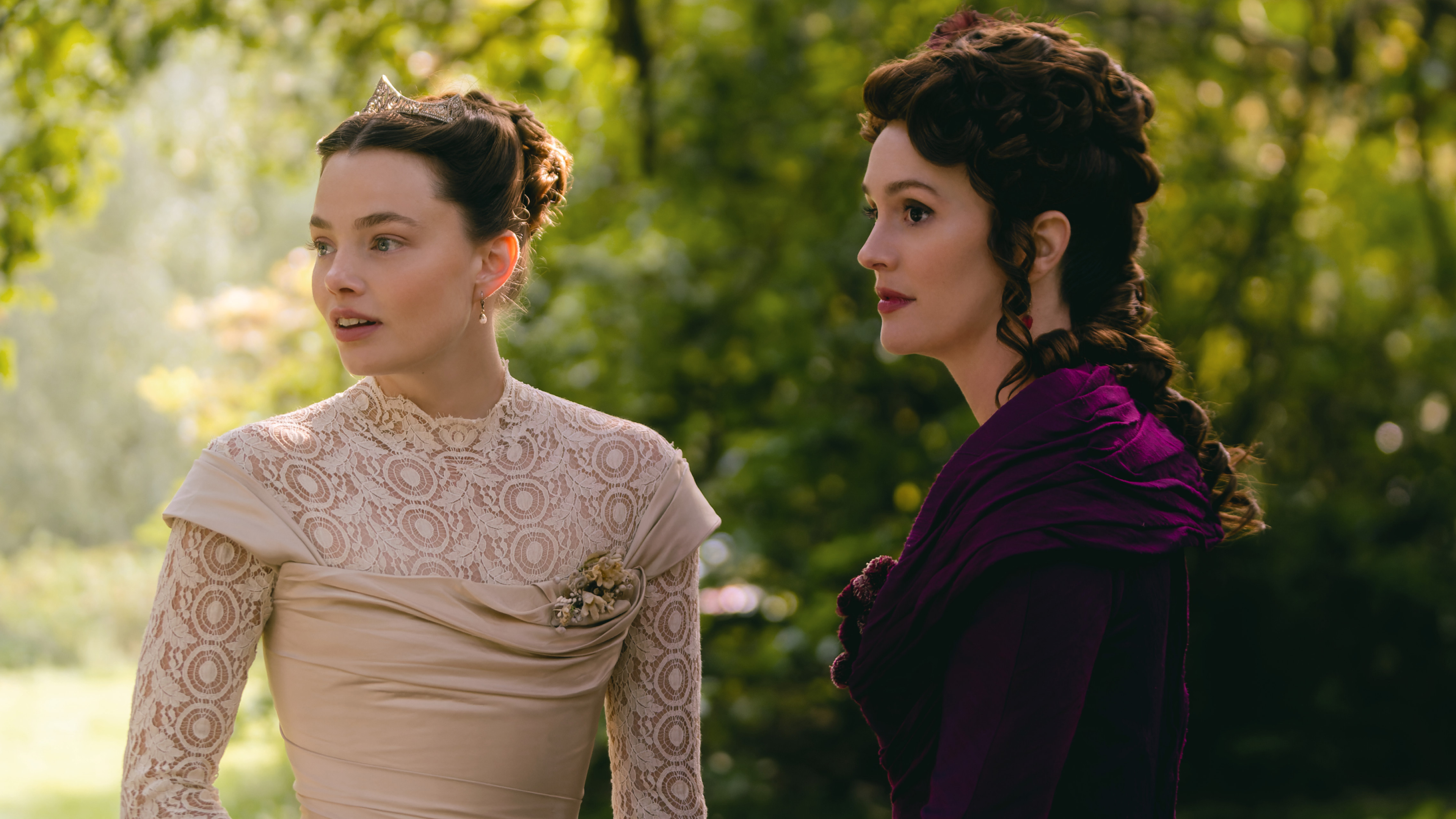 kristine froseth in a white dress and leighton meester in a purple gown speaking in a field in the buccaneers season 2