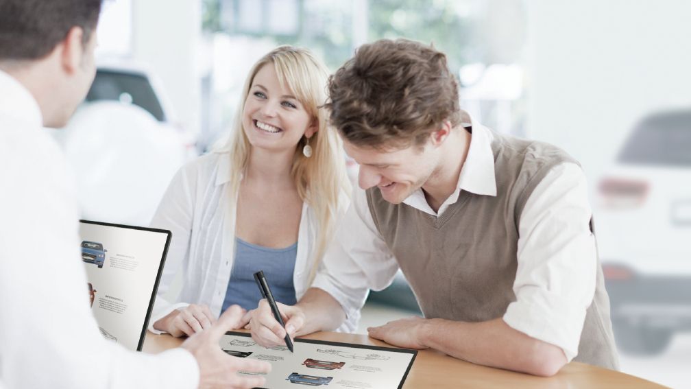 3 people working at a table with a tablet and a stylus pen