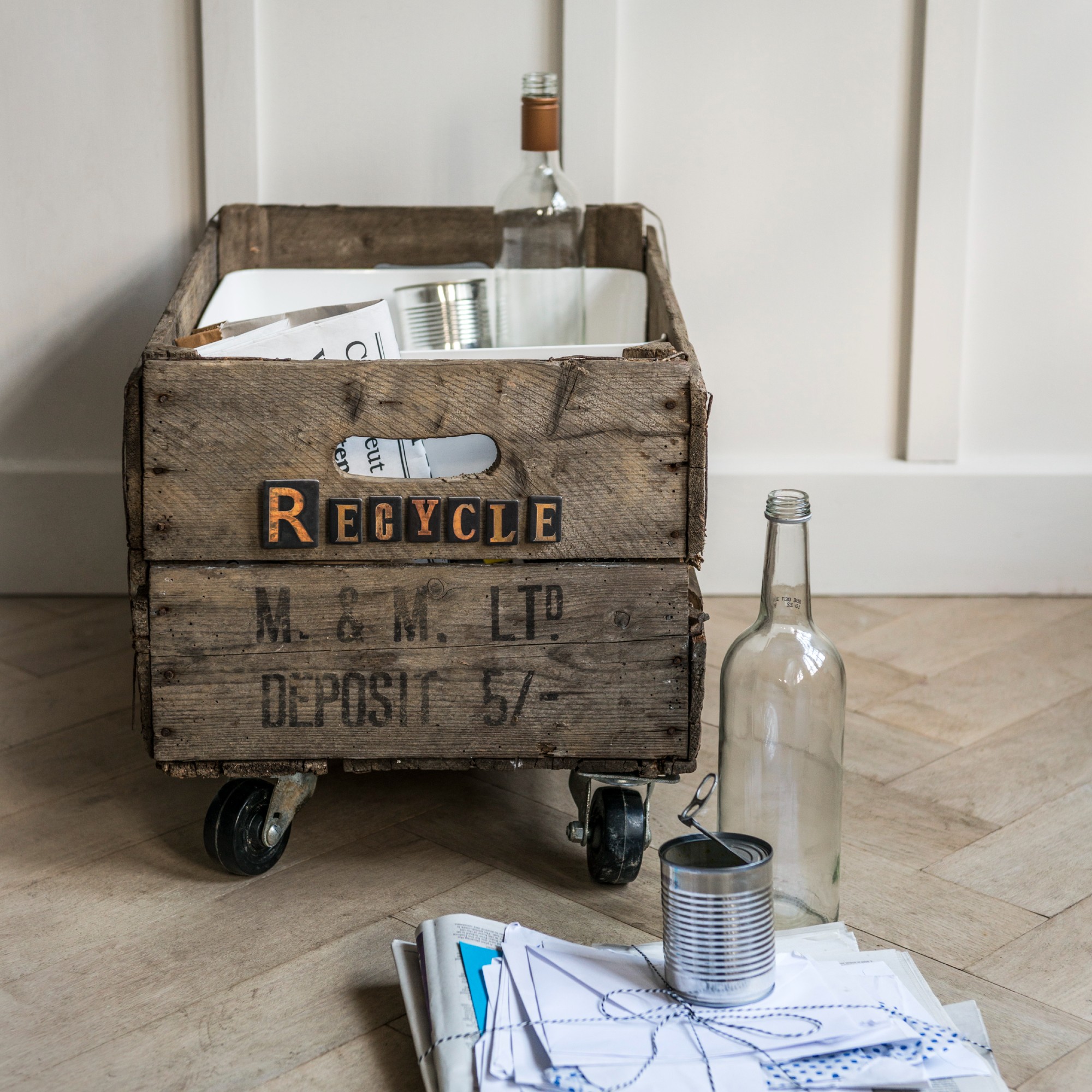 An old wooden crate with castor wheels on the bottom used for recycling