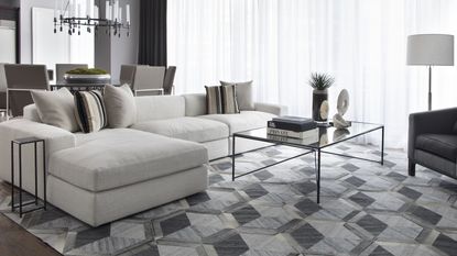 Living room with sectional sofa in neutral, gray geometric pattern rug and glass coffee table