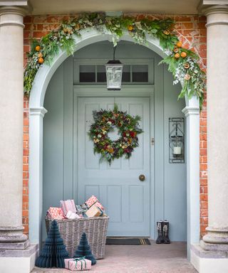 A front door decorated for christmas with a basket of presents and a wreath