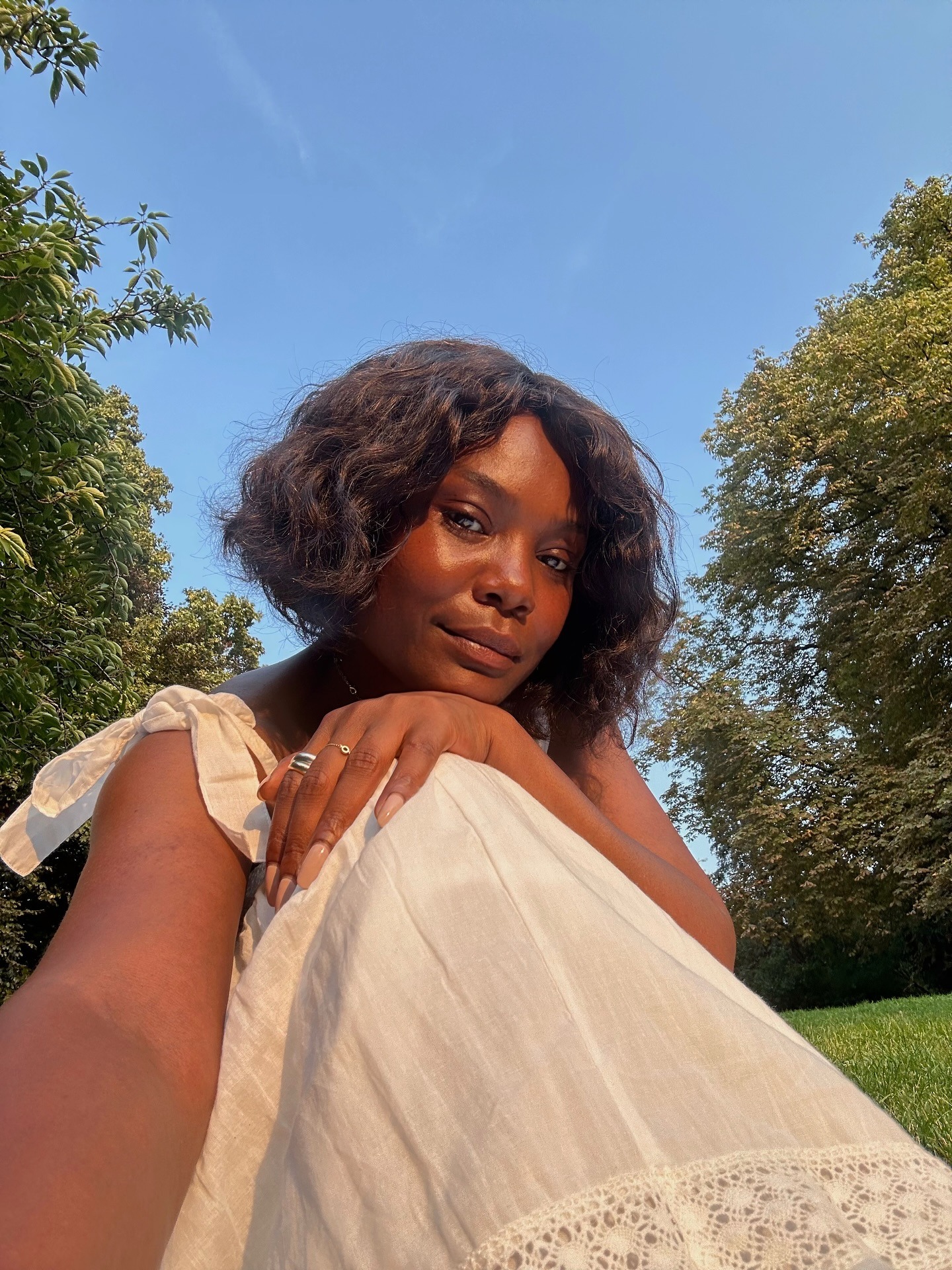 Creator @frannfyne taking a selfie in the sun with a curly bob hairstyle and side parting